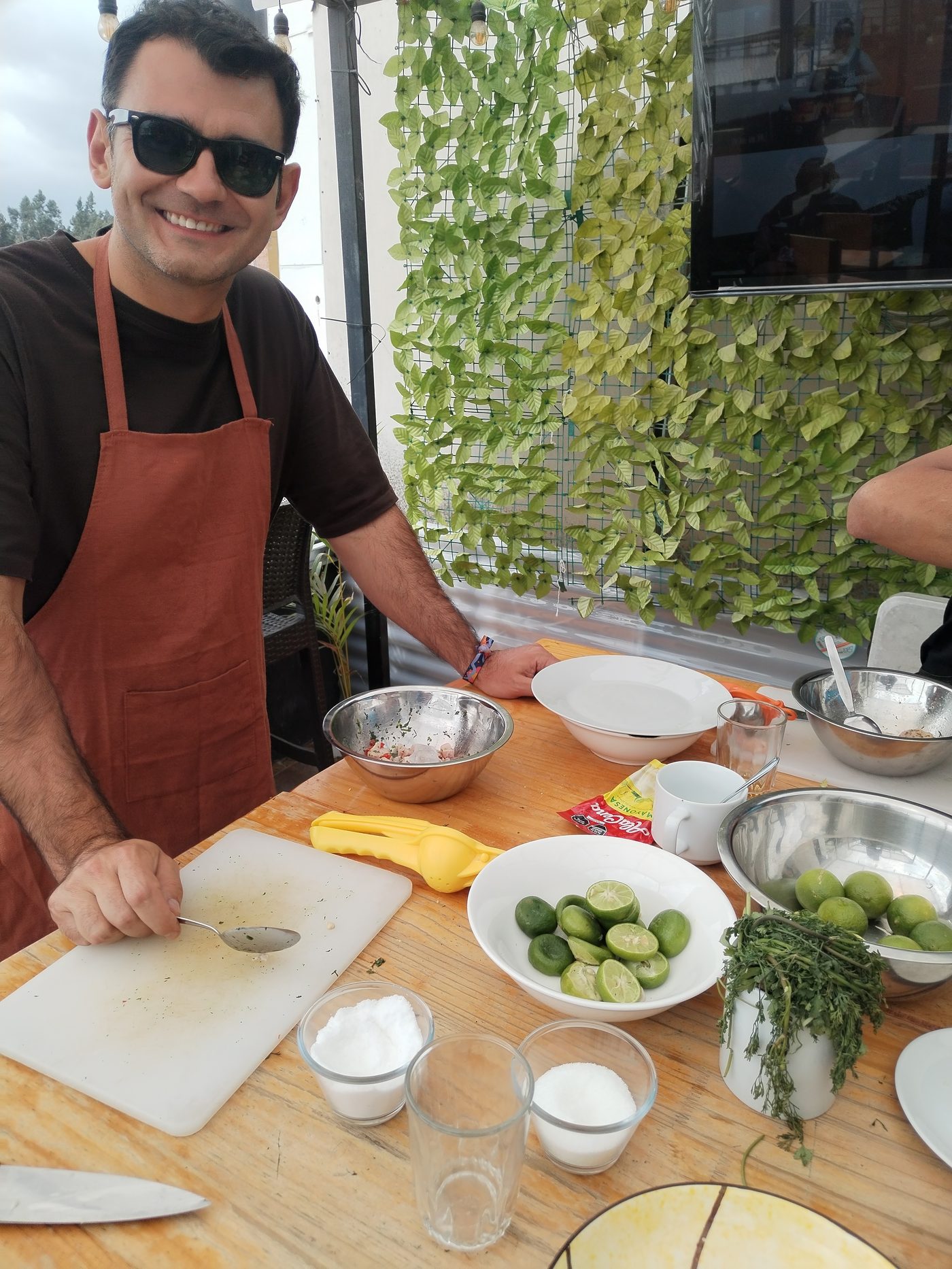 Huallata guide in an apron preparing fresh ceviche at the class table, with limes, herbs and mixing bowls in front of him