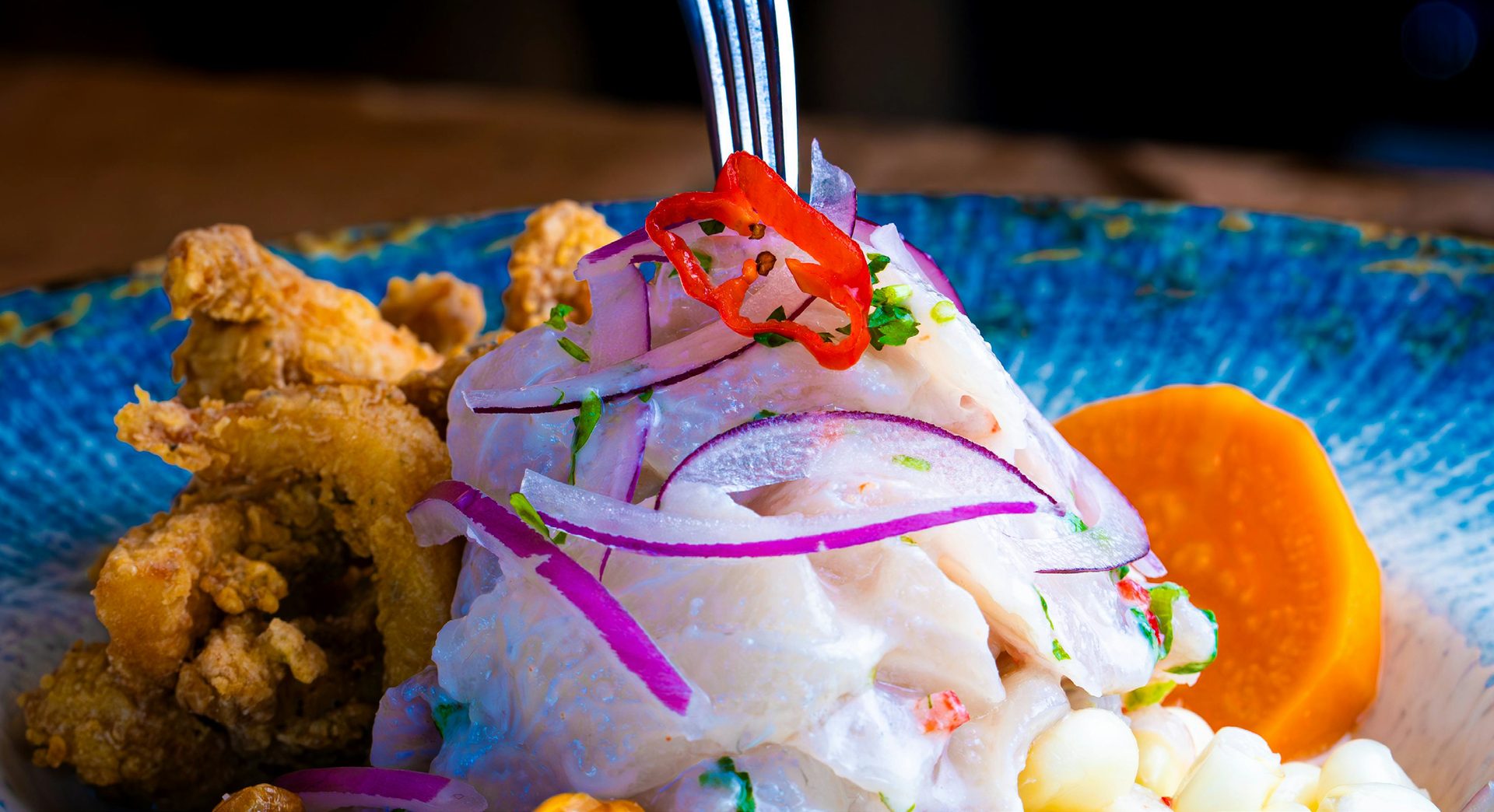 Freshly plated Peruvian ceviche with red onion and sweet potato at a cooking class table