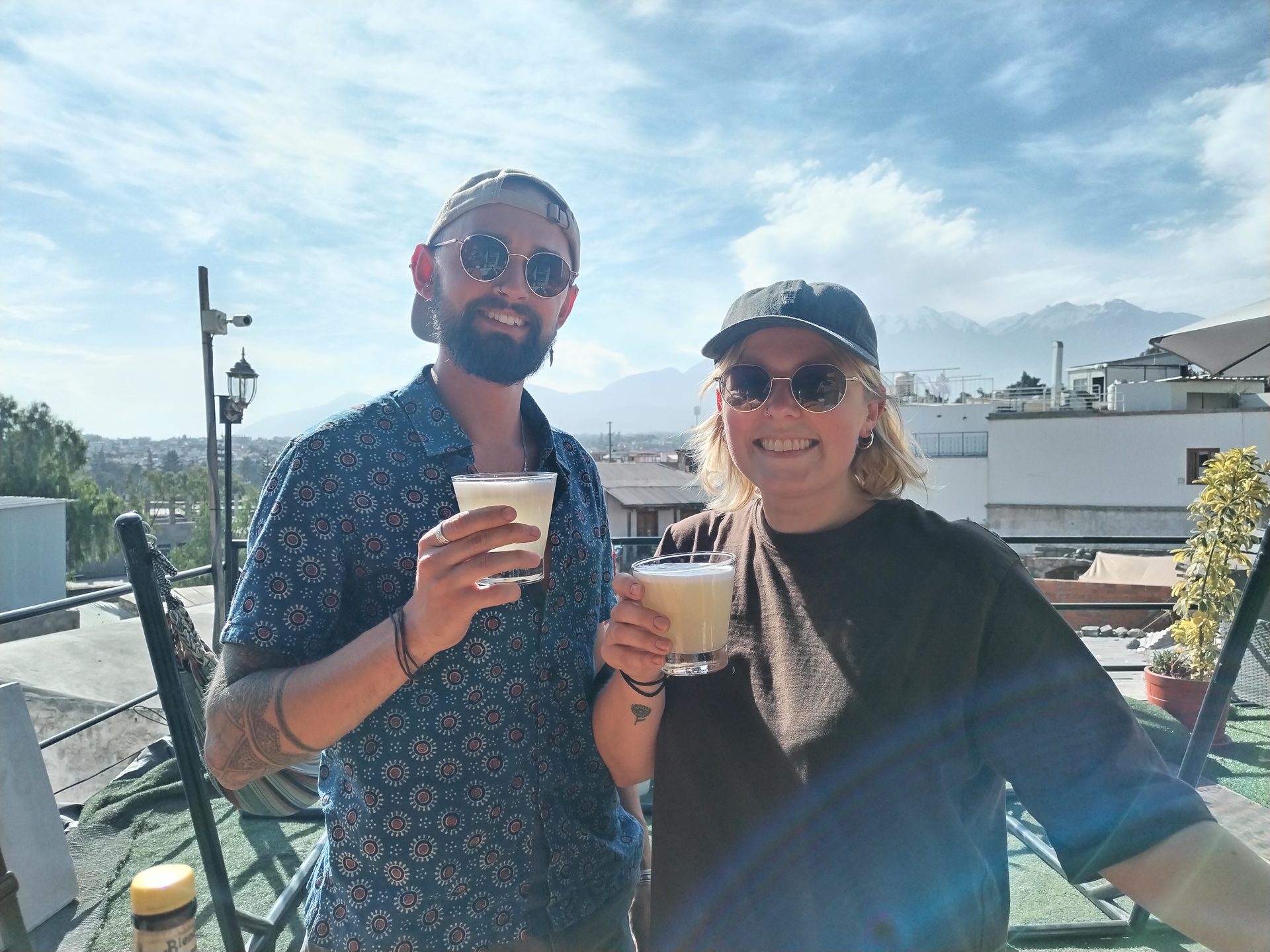 Hands straining a frothy pisco sour into a glass on a rooftop terrace above the White City